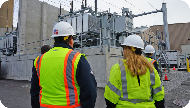 Two UI employees with  hard hats and safety vests in front of our Congress St Flood Wall project